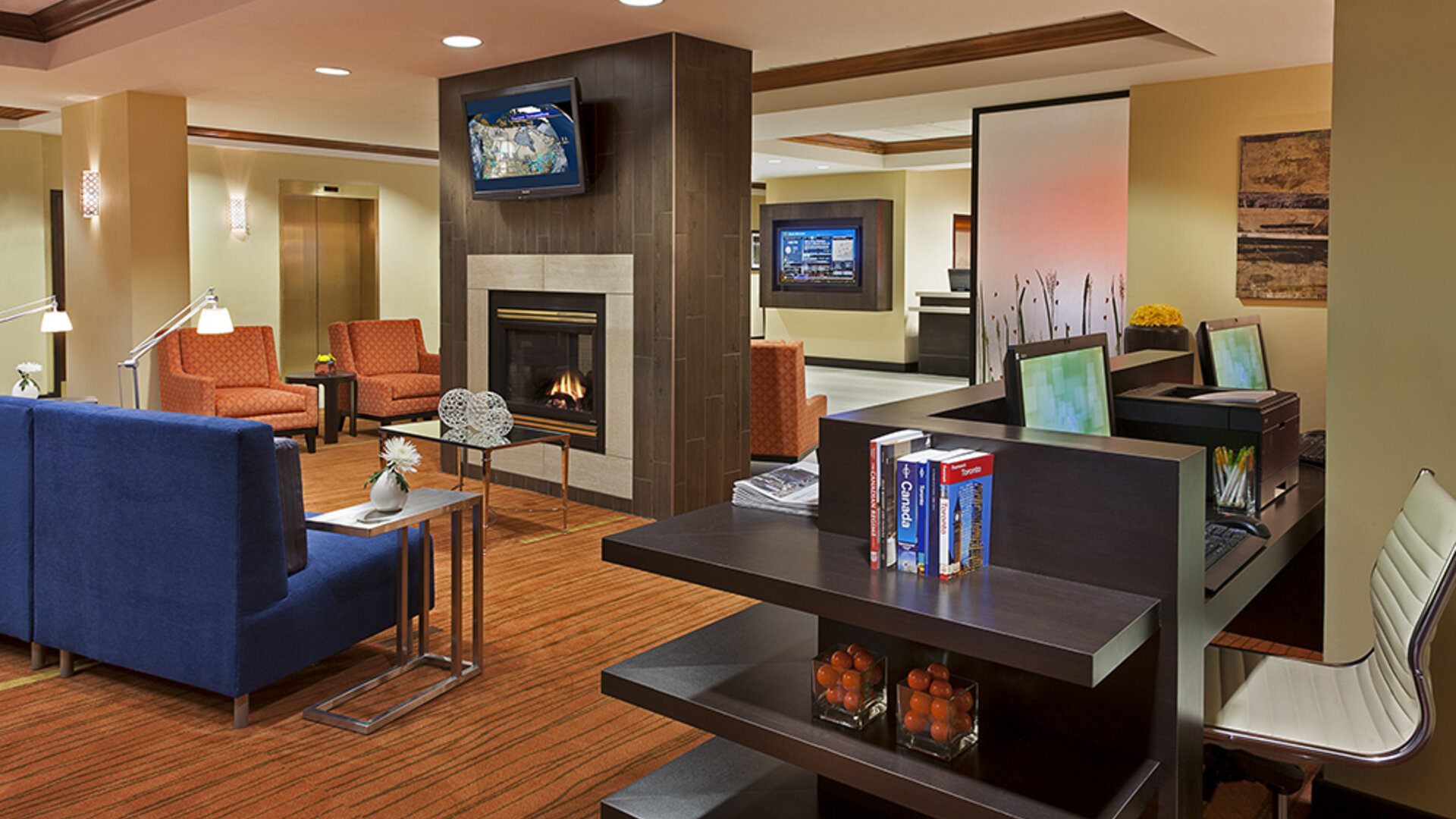 Lobby lounge area with fireplace and business center with computers and printer at Courtyard By Marriott Toronto Airport.