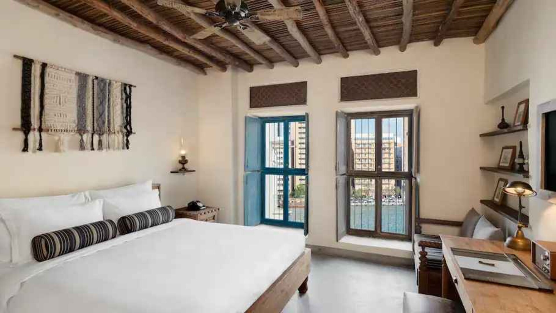 Bright room with king size bed, desk and windows at the Al Seef Heritage Hotel Dubai, Curio Collection by Hilton.