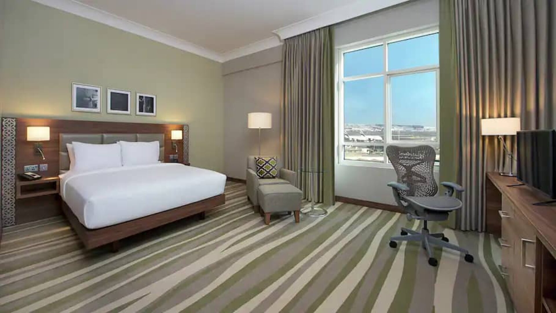 Large hotel room with king-size bed, great view of the city and spacious work area.