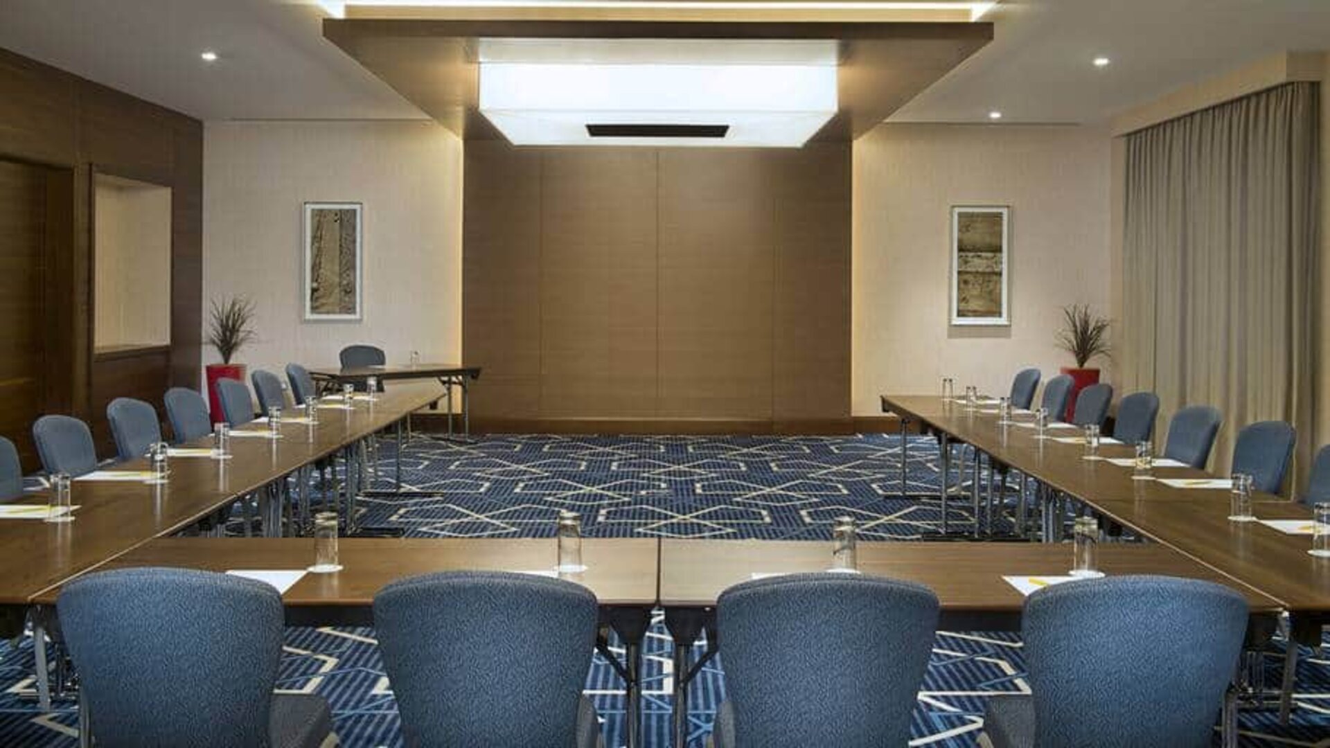 Spacious conference room with tables and chairs and a big wall for screenings at the Hilton Garden Inn Dubai Al Mina
