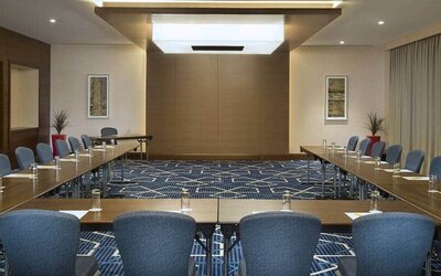 Spacious conference room with tables and chairs and a big wall for screenings at the Hilton Garden Inn Dubai Al Mina