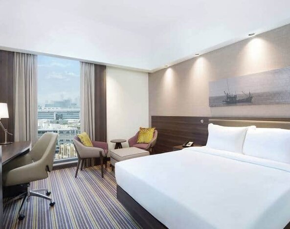 Spacious room with queen bed, desk and chair area at the Hampton Dubai Airport
