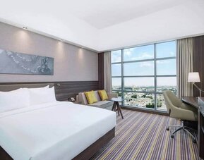 Spacious room with queen bed, pull out sofa, desk and chair area at the Hampton Dubai Airport