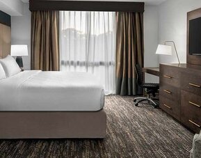 Comfortable king bed with TV and work area at Embassy Suites by Hilton Nashville Airport.