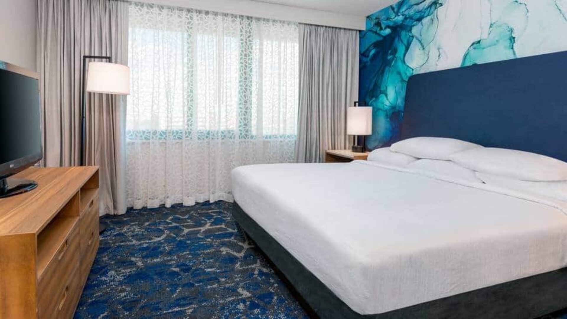 Spacious room with king size bed, tv and media console at the Embassy Suites by Hilton Tampa USF