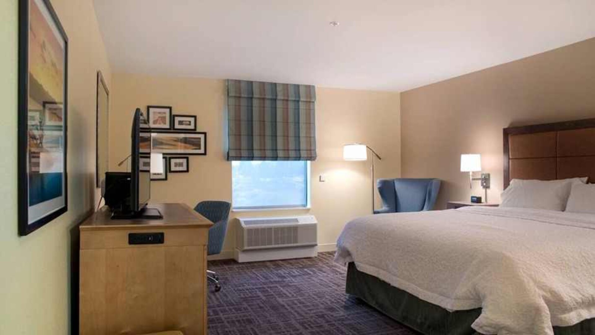 Comfortable king-sized bed with work area at Hampton Inn Big Rapids, MI.