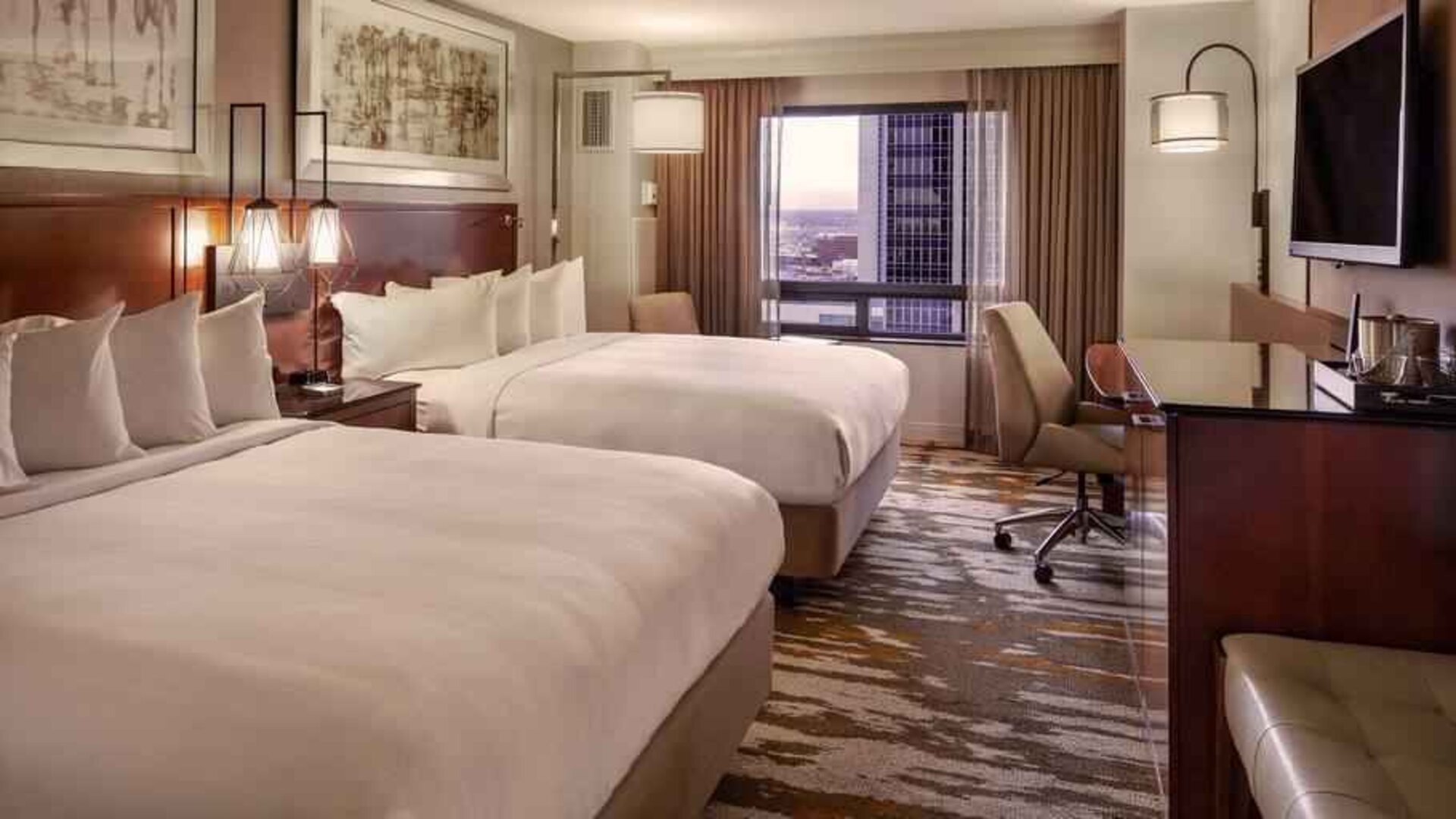 Stylish bedroom with two queen size beds, desk and TV screen at the Hilton Denver City Center.