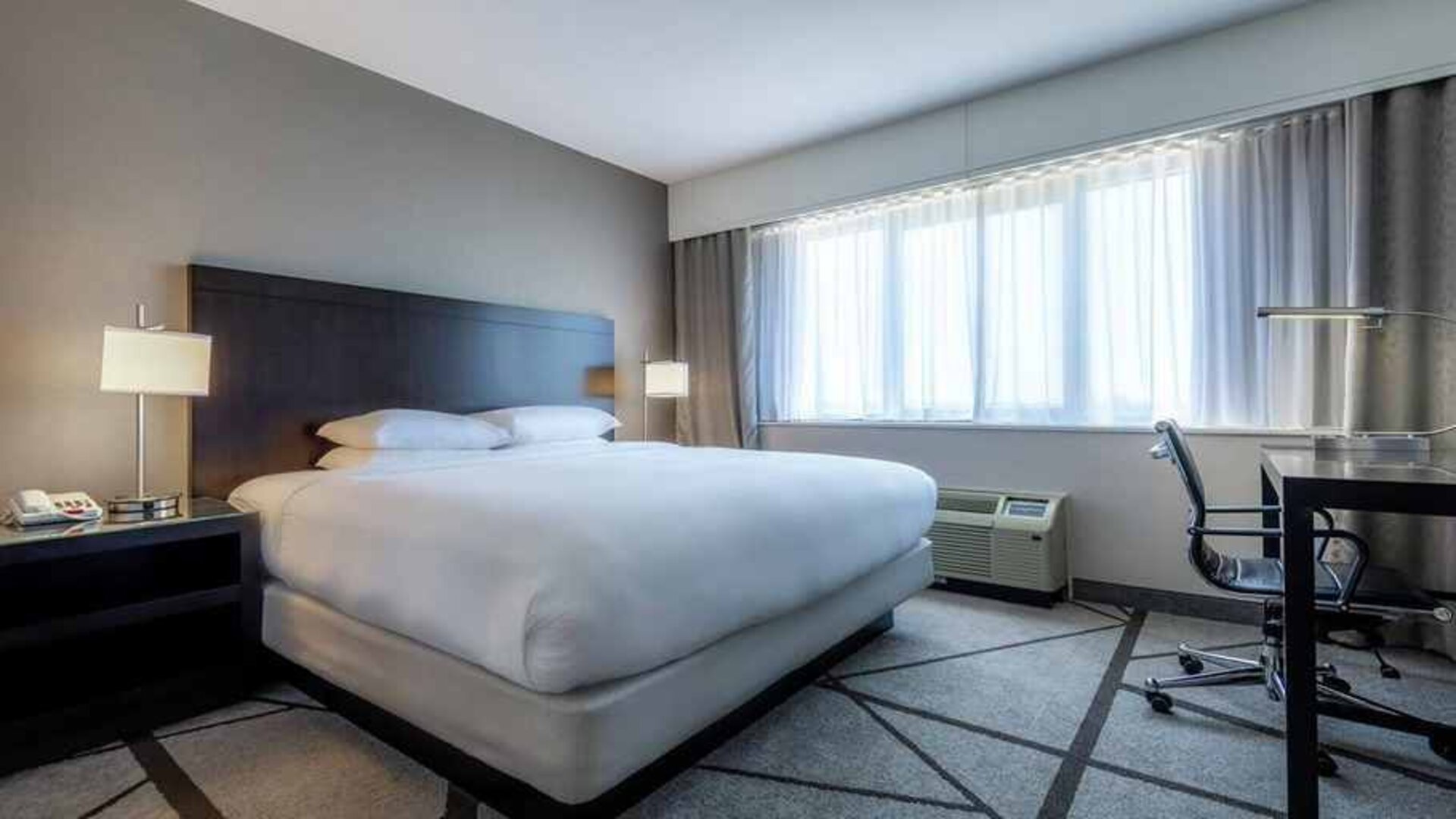 king-sized bed equipped with TV and work desk and with natural light at DoubleTree by Hilton Los Angeles - Norwalk.