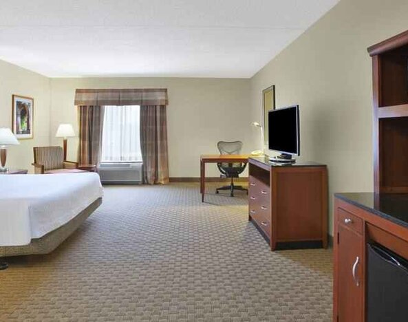 Spacious and bright king guestroom with TV and desk at the Hilton Garden Inn Clarksburg.