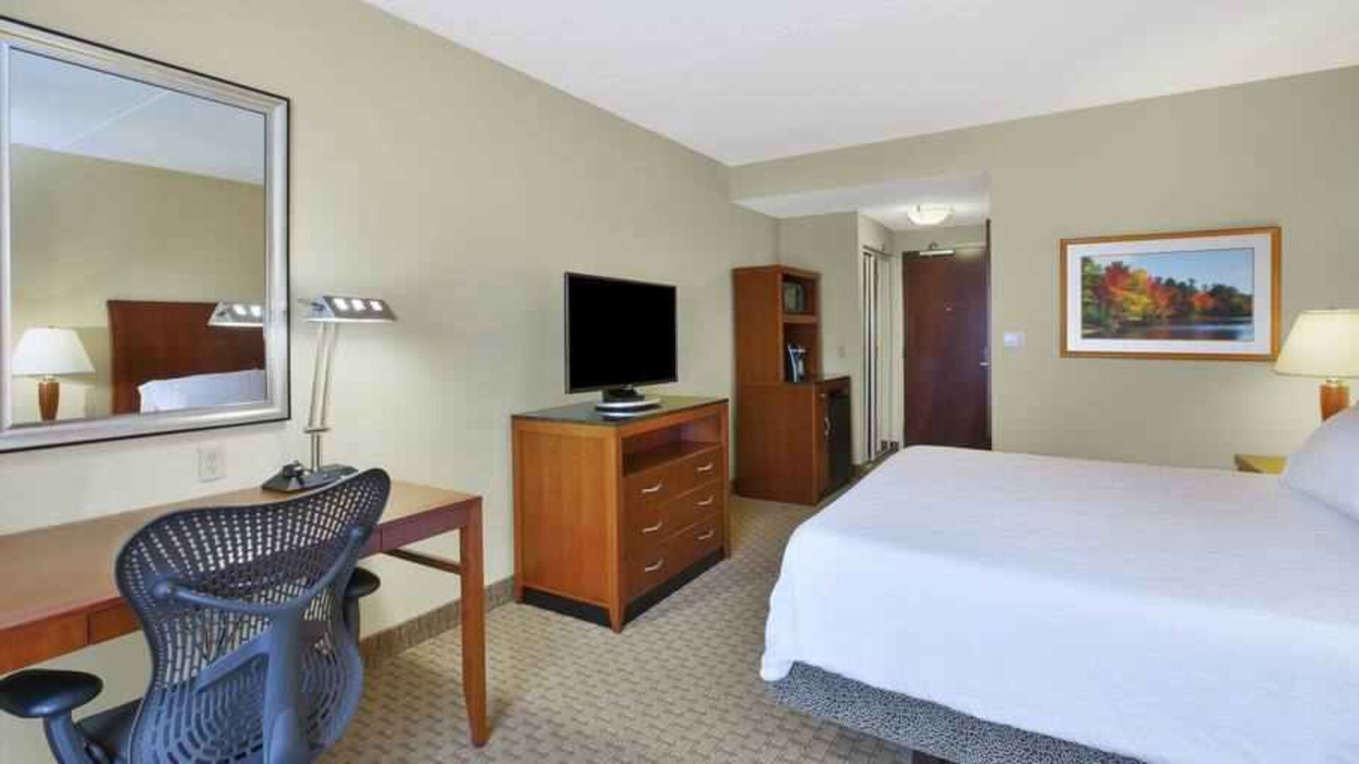 King size bed, desk and TV screen in a hotel room at the Hilton Garden Inn Clarksburg.