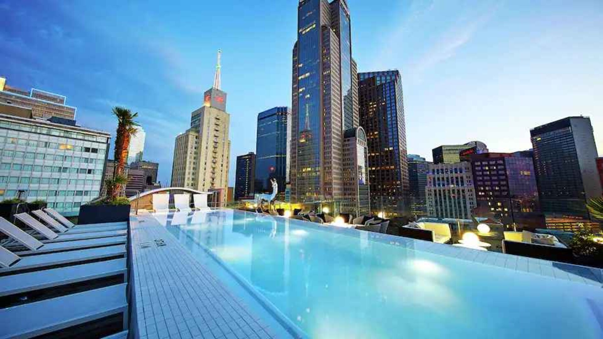 Relaxing outdoor pool with skyline view at the Statler Dallas, Curio Collection by Hilton.