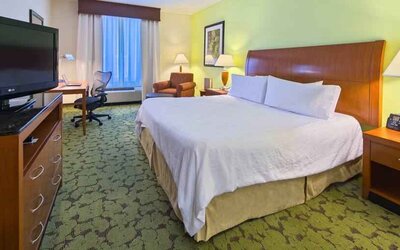 King size bed, TV screen and desk in a hotel room at the Hilton Garden Inn Tallahassee Central.