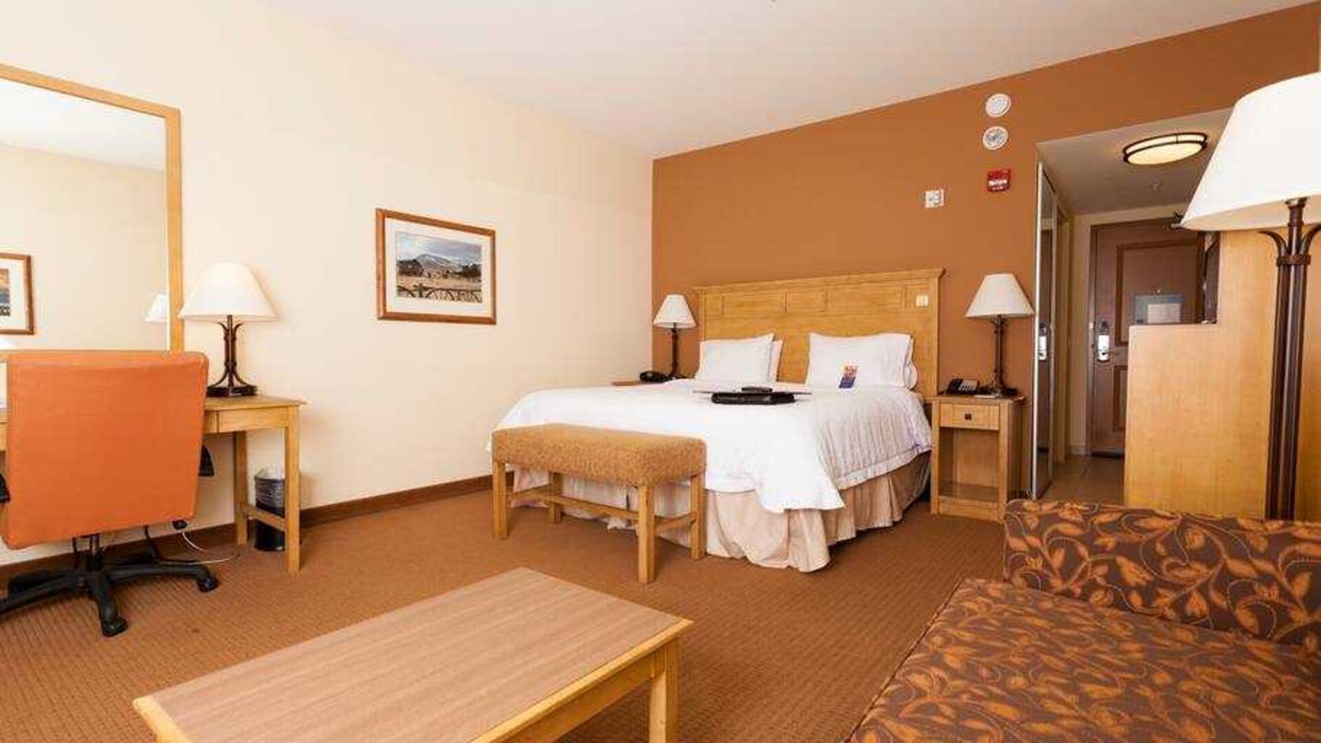 Spacious king suite with sofa and desk at the Hampton Inn & Suites Riverton, WY.