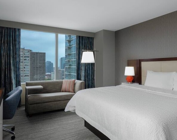 Comfortable king suite with desk, sofa and window at the Hampton Inn Chicago McCormick Place.