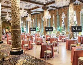 Elegant event room with big windows, lovely chandeliers and intricate pillars at The Drake.