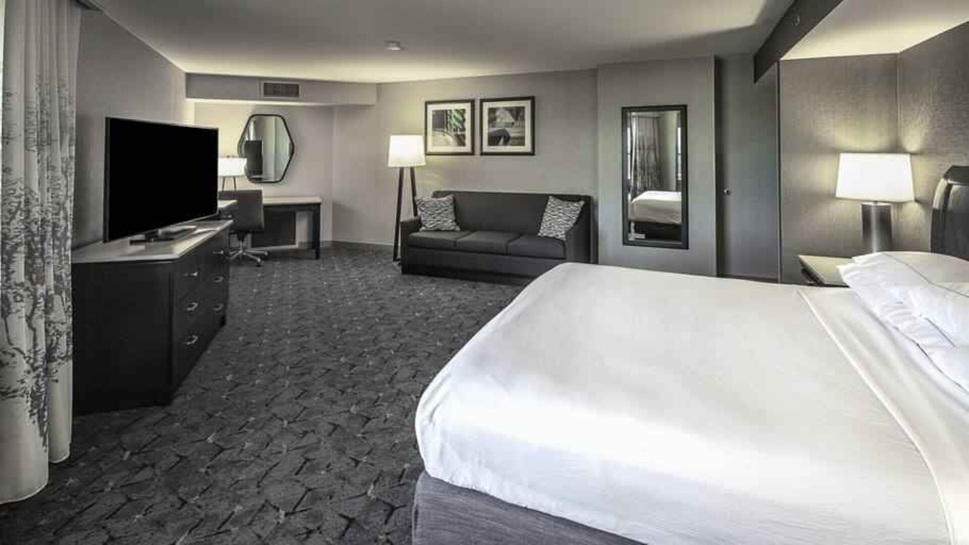 King size bed, sofa and desk in a spacious bedroom at the DoubleTree by Hilton Modesto.