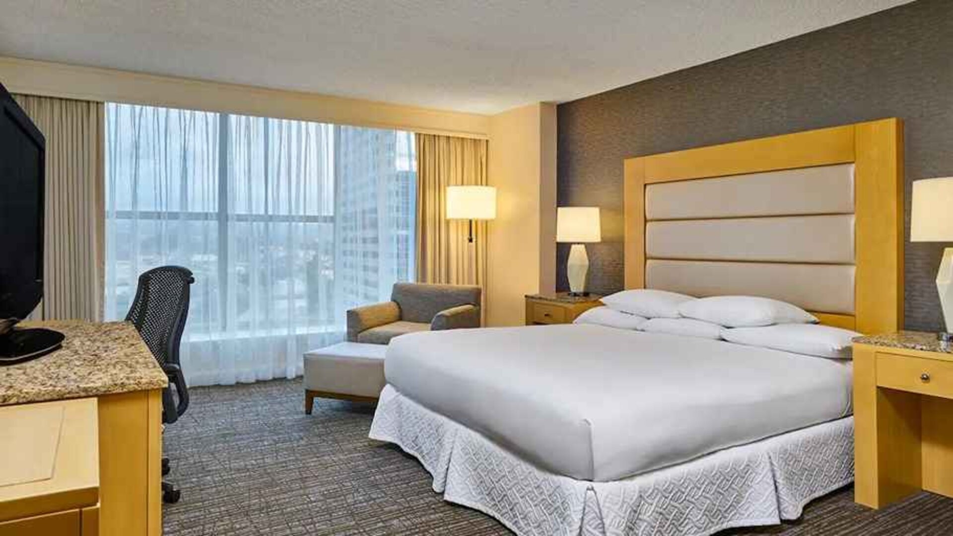 comfortable king-sized bedroom with work space and lounge area at Hilton Los Angeles North/Glendale & Executive Meeting Ctr.
