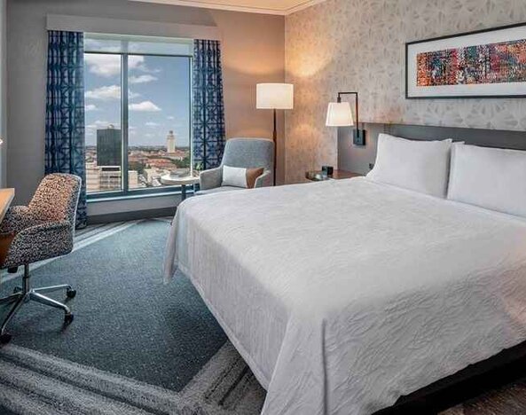 Comfortable king bedroom with city views and natural light at Hilton Garden Inn Austin University.