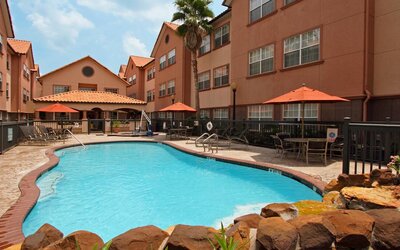 beautiful outdoor pool with sun beds and seating area at Homewood Suites by Hilton Houston-Woodlands.