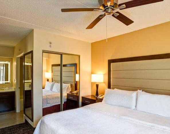 King size bed, fan and mirror in a king guestroom at the Homewood Suites by Hilton Washington, D.C. Downtown.