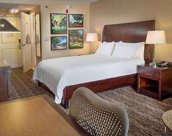 spacious king bedroom with TV, lounge area, and work desk ideal for working remotely at Hilton Garden Inn St. Louis Airport.