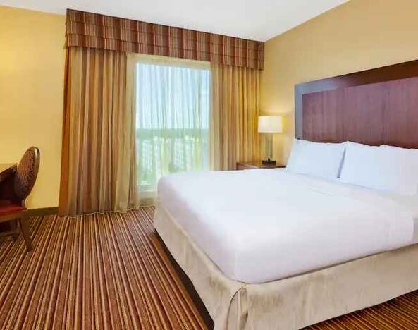 King size bed, window and desk in a king room at the Embassy Suites by Hilton Nashville SE Murfreesboro.