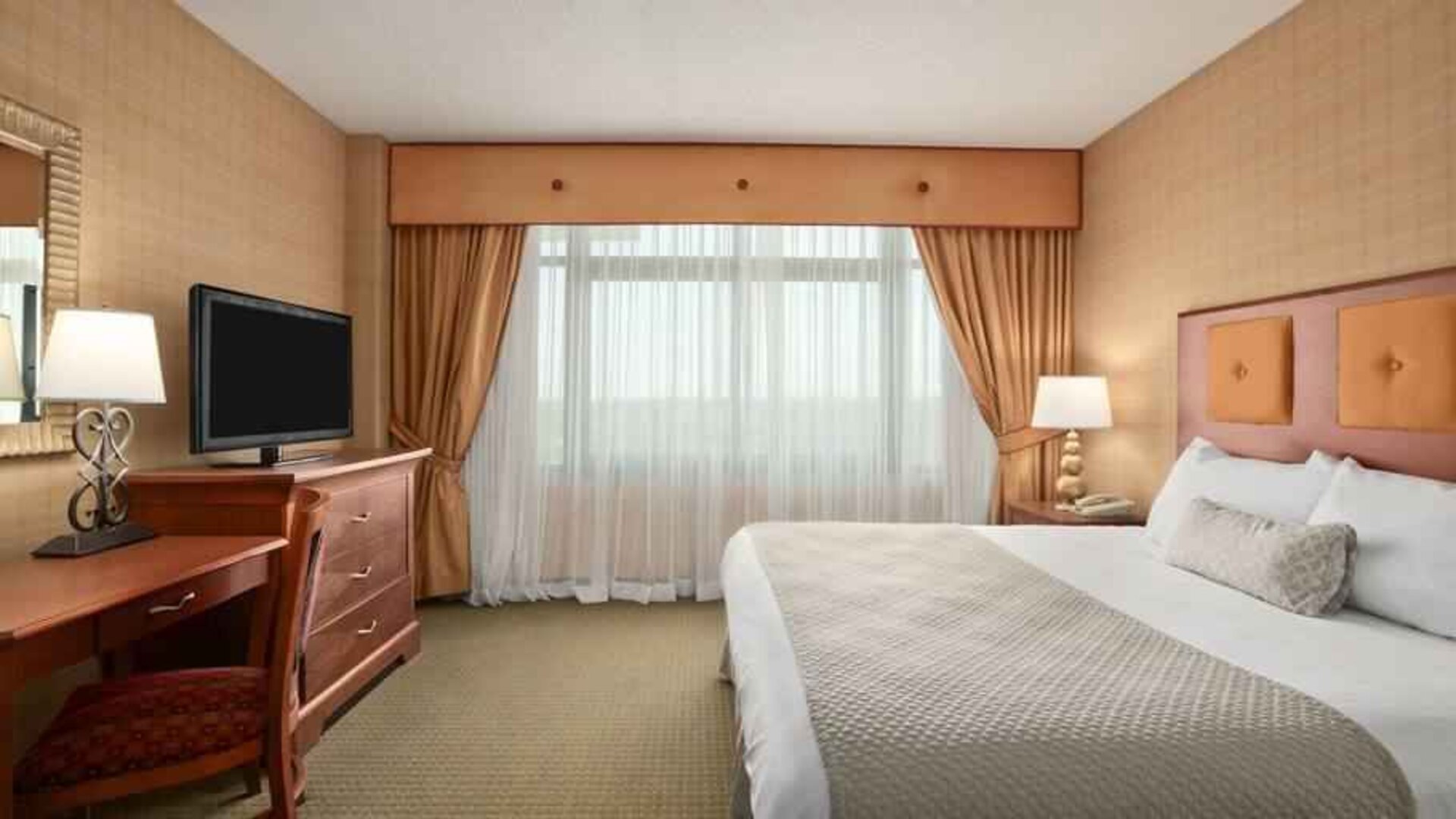 King bedroom with TV screen and desk at the Embassy Suites by Hilton Hot Springs Hotel & Spa.
