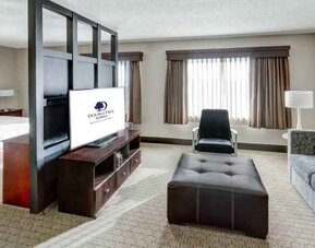 Spacious king suite with TV screen and sofa at the DoubleTree by Hilton Wichita Airport.