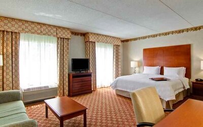 Spacious guestroom with king size bed, sofa and TV screen at the Hampton Inn & Suites Leesburg.
