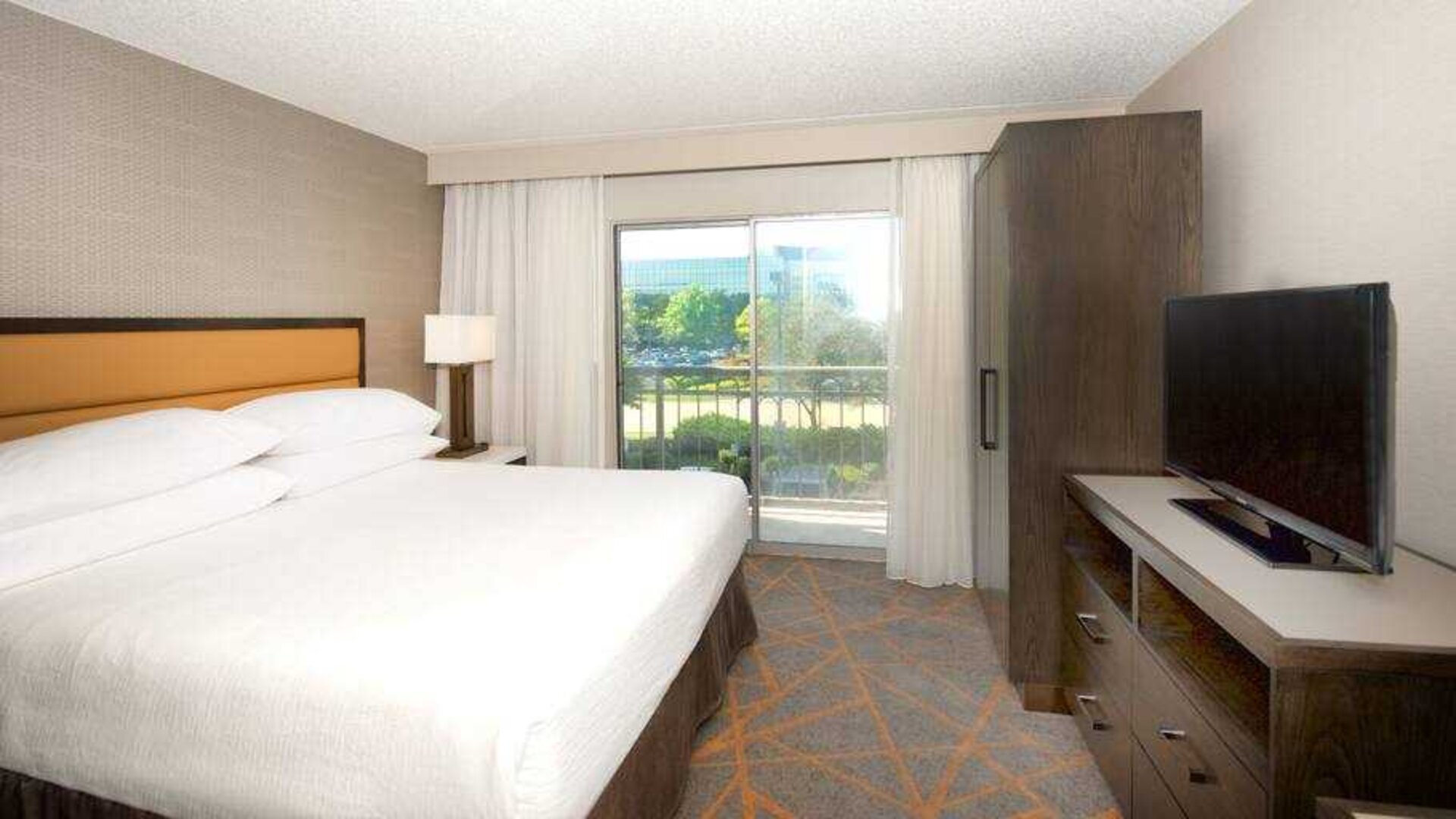 King bedroom with window and TV screen at the Embassy Suites by Hilton Cincinnati Blue Ash.