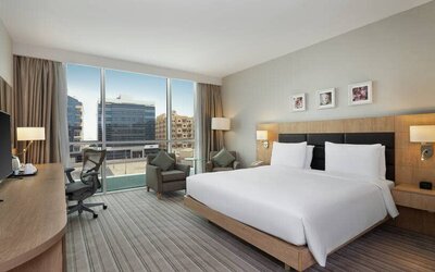 King-sized bed with view of city buildings at the Hilton Garden Inn Dubai Mall of the Emirates.