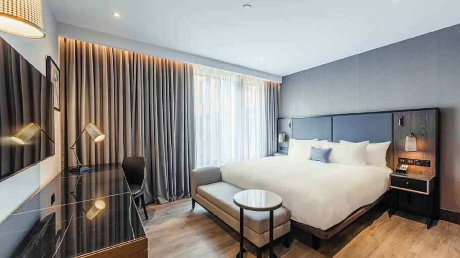 Bright king bedroom with desk at the Fellows House Cambridge, Curio Collection by Hilton.