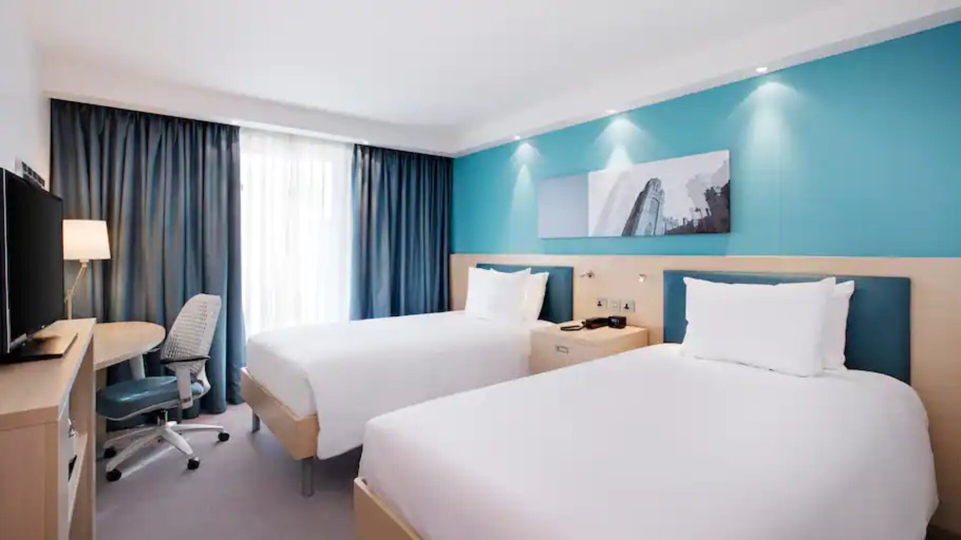 Twin room with TV screen and desk at the Hampton by Hilton Bristol Airport.