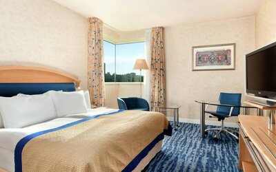 Bright, spacious king guest suite with television, king bed and work space at the HIlton Sofia, in Bulgaria.