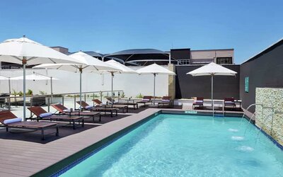 Narrow rectangular pool with fountains coming out of side wall, abundant lounge chairs for sunbathing.