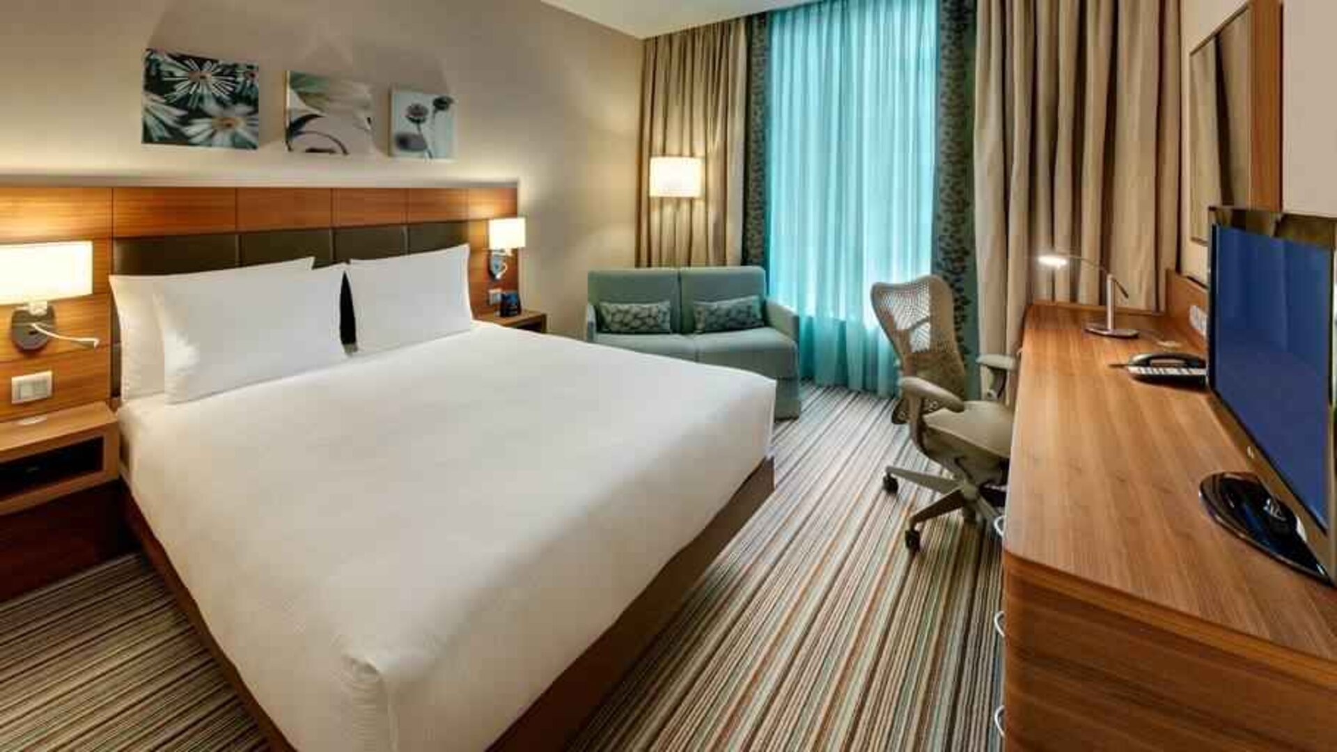 Queen room with desk and sofa at the Hilton Garden Inn Frankfurt Airport.