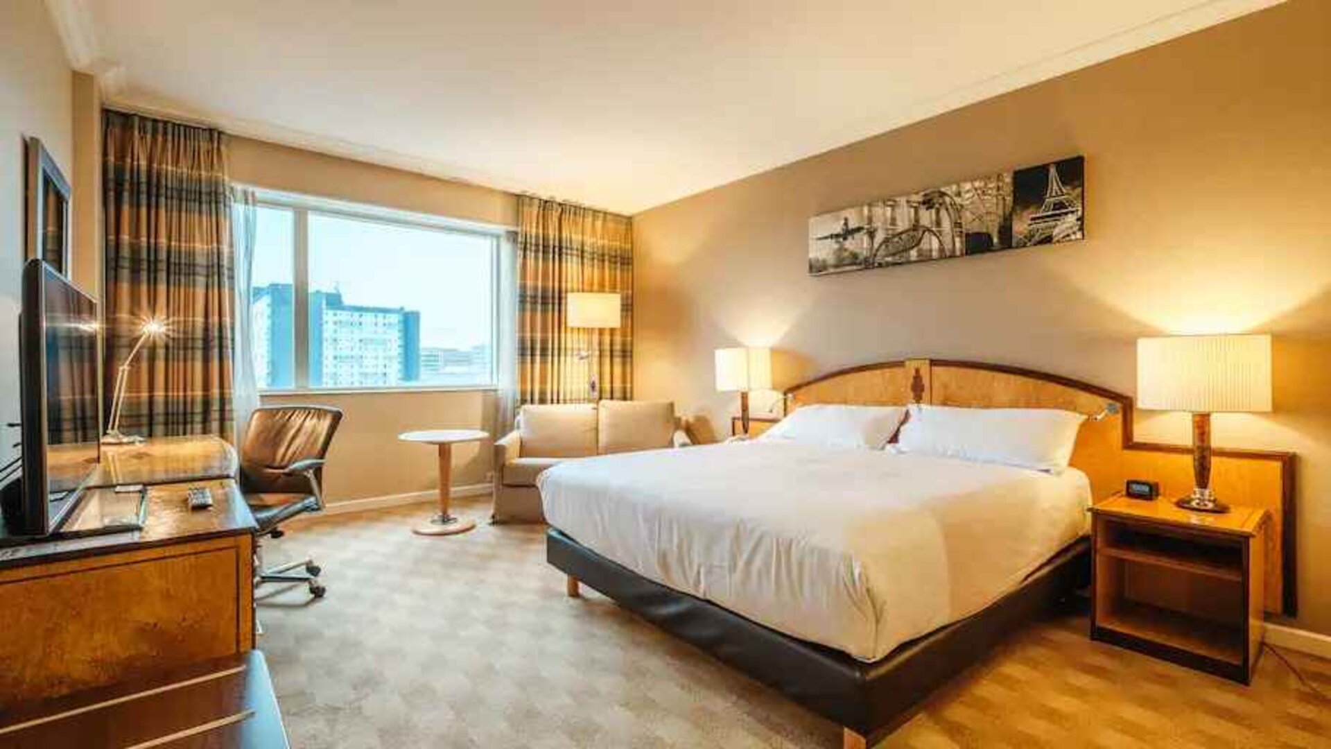 King bedroom with soafa and desk at the Hilton Paris Charles de Gaulle Airport.