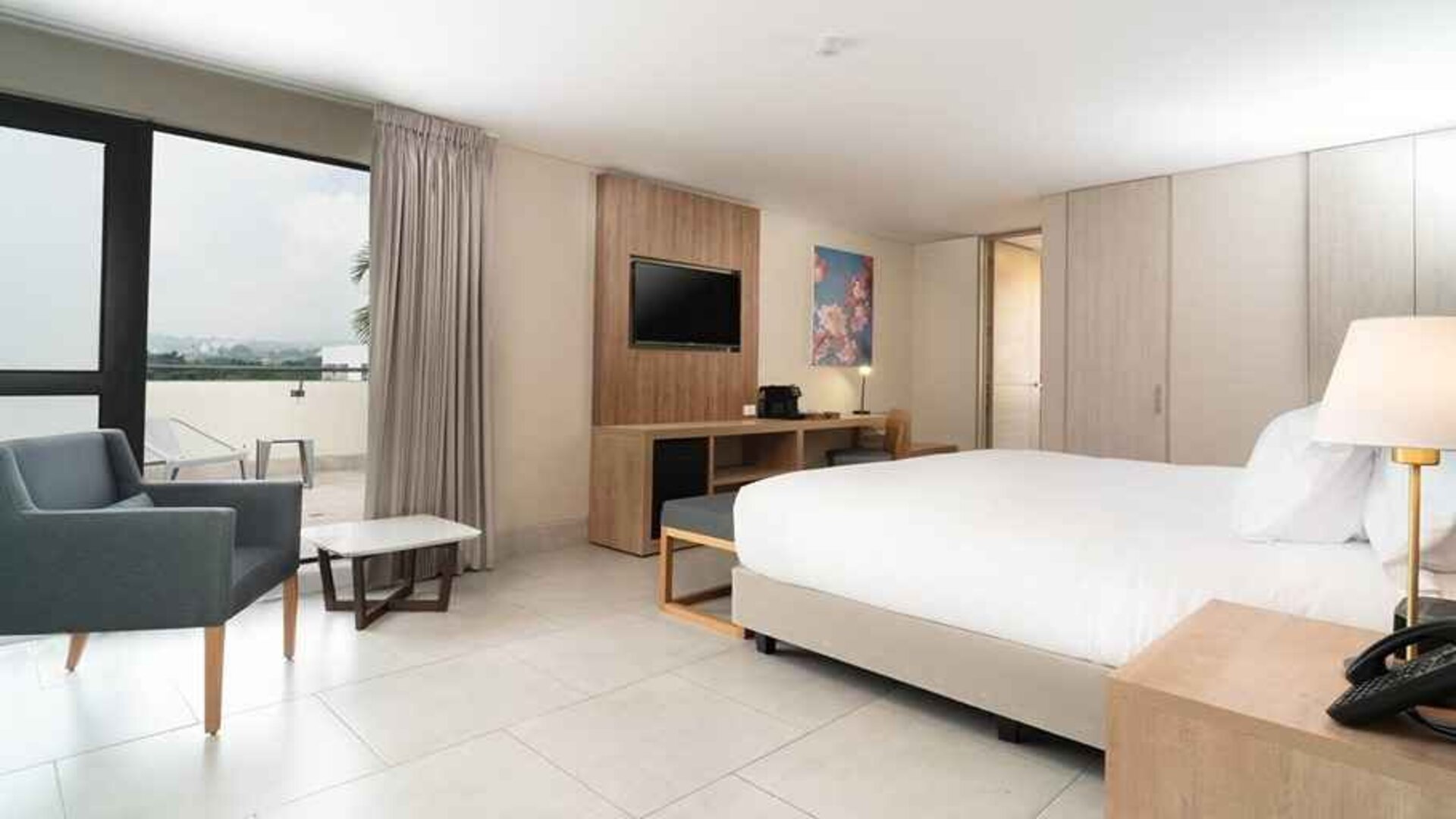 beautiful king suite with TV, lounge area, and lots of natural light at Hilton Garden Inn Cali Ciudad Jardin.