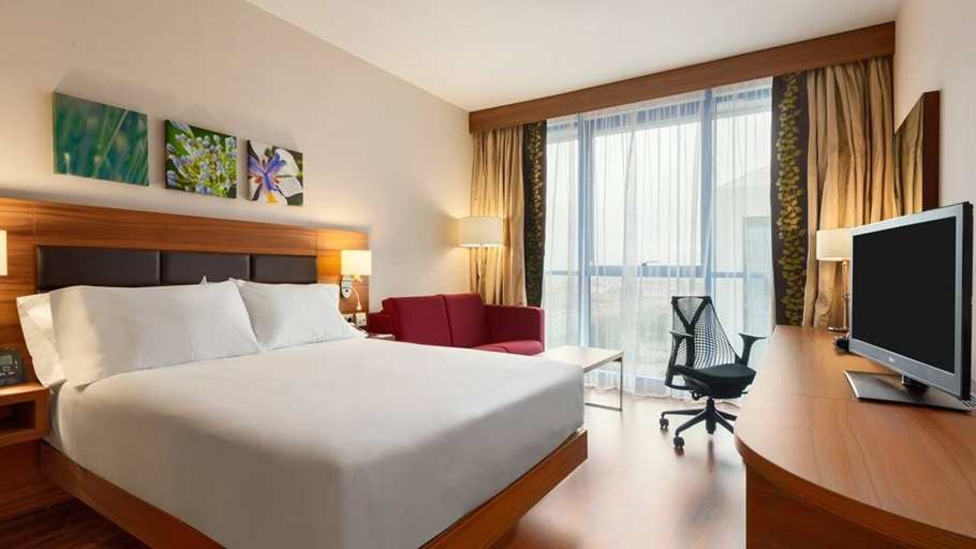 comfortable king bed with work desk, TV, and large windows at Hilton Garden Inn Sevilla.