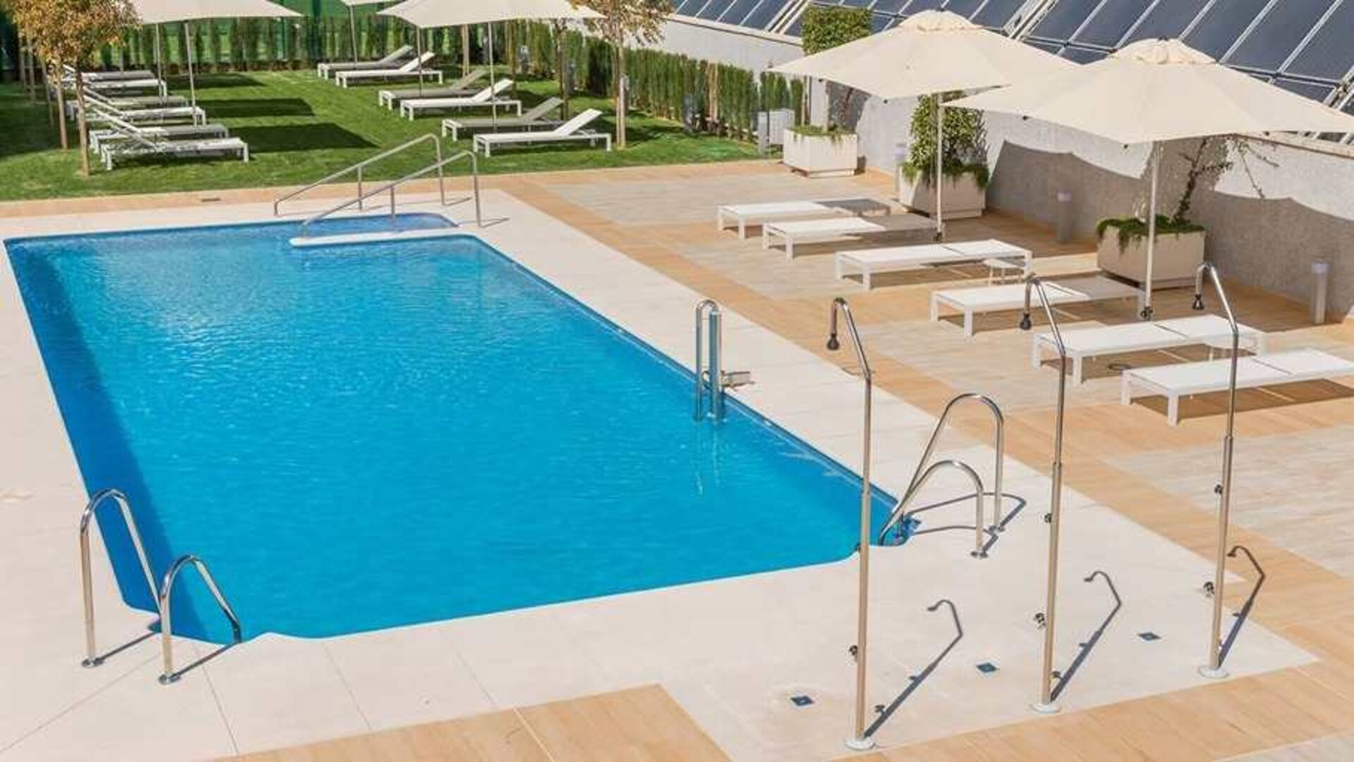 stunning outdoor pool with sun beds and umbrellas at Hilton Garden Inn Sevilla.