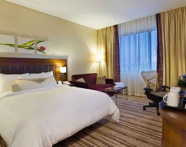 spacious king bedroom with TV, desk, chair, couch, and coffee station at Hilton Garden Inn Kutahya.