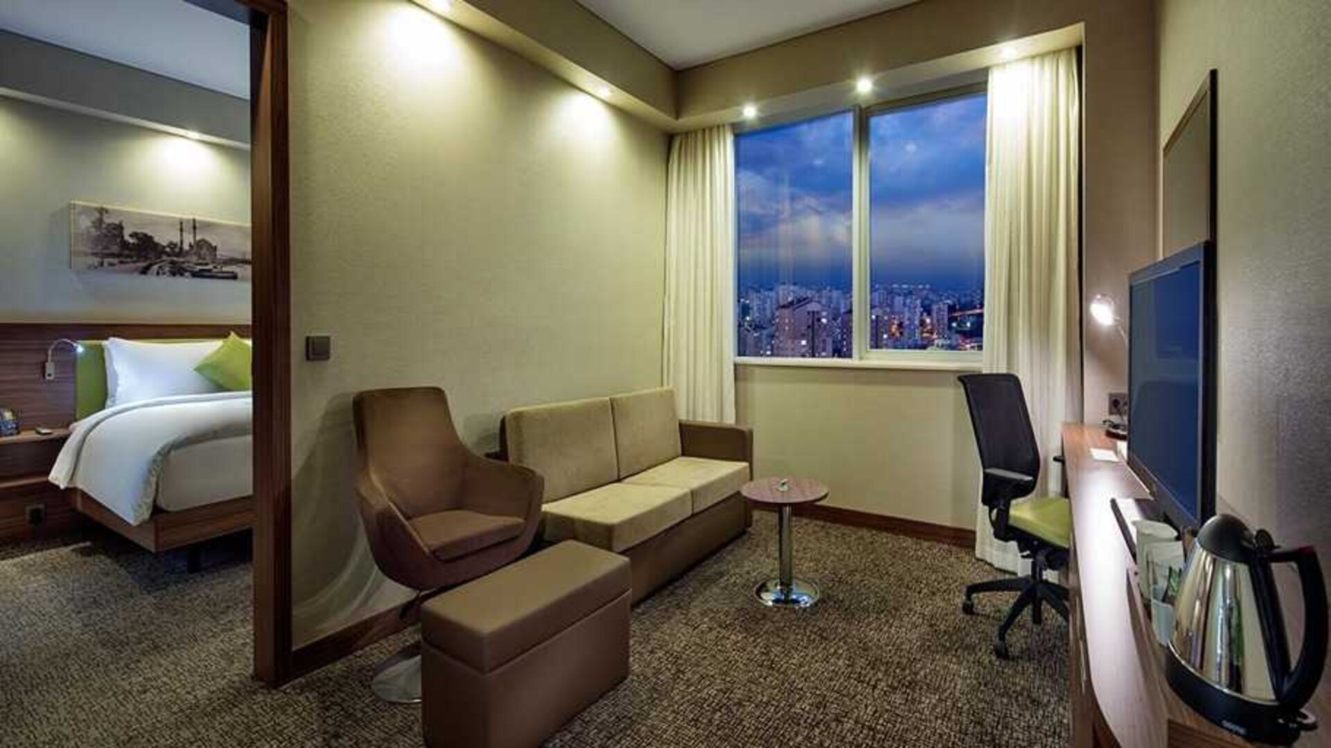 spacious king suite with TV, work desk and chair, lounge area, and coffee station at Hampton by Hilton Istanbul Kayasehir.
