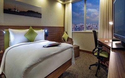 comfortable king bedroom with TV, desk, and chair at Hampton by Hilton Istanbul Kayasehir.