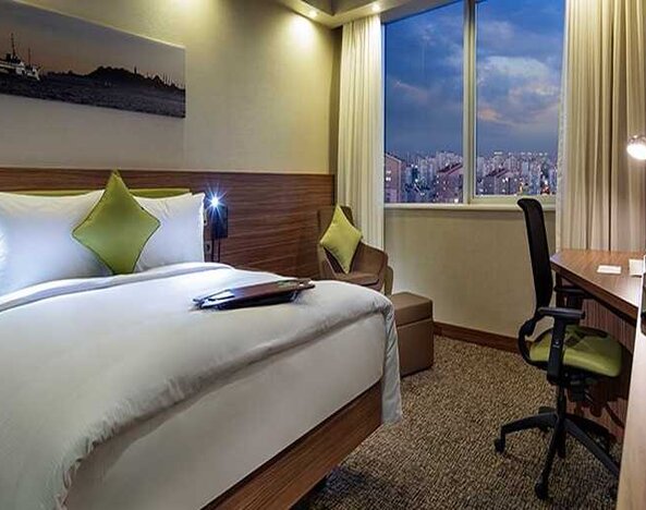 comfortable king bedroom with TV, desk, and chair at Hampton by Hilton Istanbul Kayasehir.
