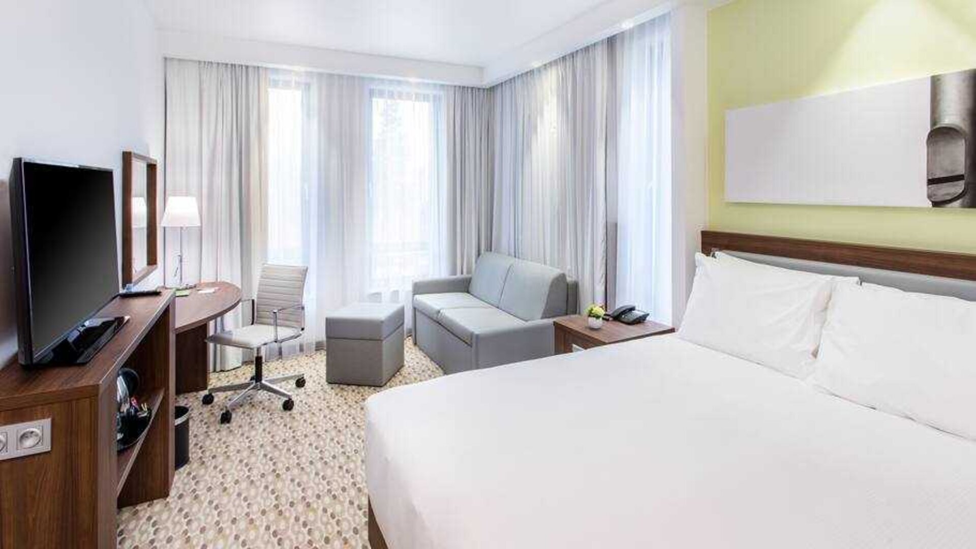 Queen room with sofa, desk and TV screen at the Hampton by Hilton Gdansk Oliwa.