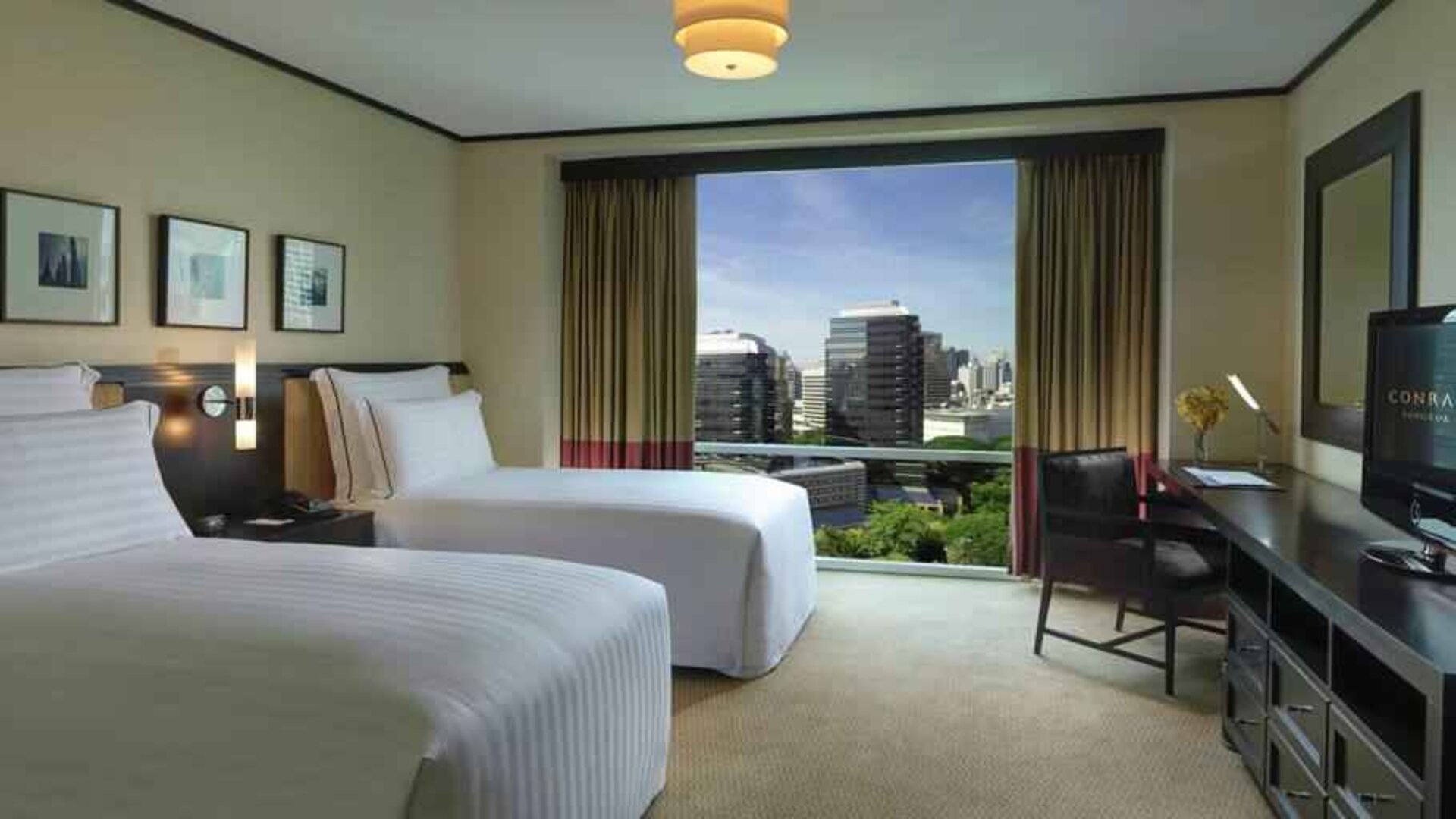 Twin room with TV screen and desk at the Conrad Bangkok.