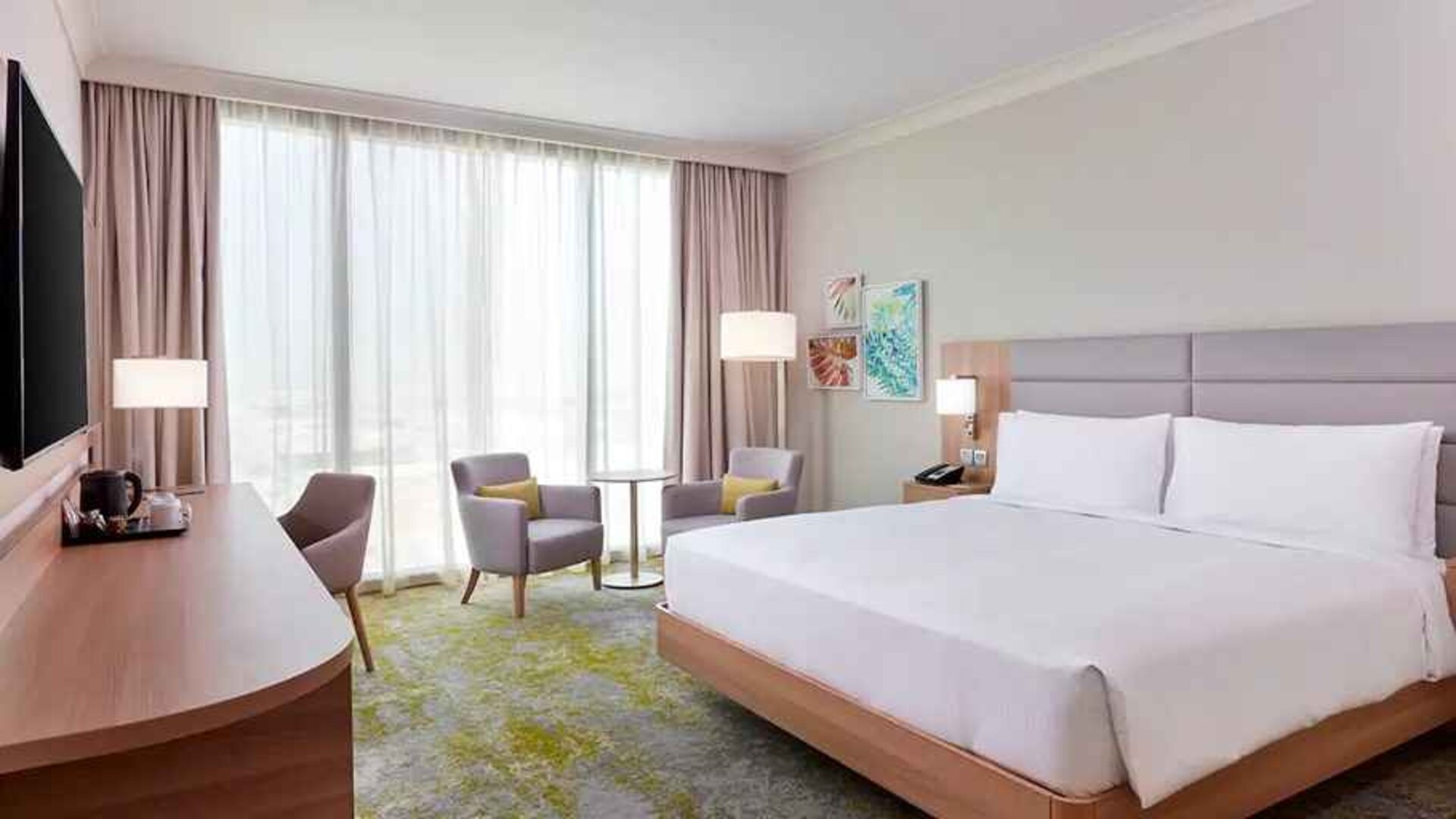 spacious king room with TV, business desk, chair, and couch at Hilton Garden Inn Kuwait.