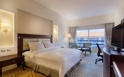 lovely king suite with TV, lounge area, work desk, and chair at Hilton Alexandria Green Plaza.