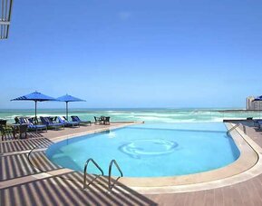 stunning outdoor pool with sunbeds and umbrellas at Hilton Alexandria Corniche.