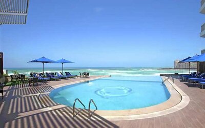 stunning outdoor pool with sunbeds and umbrellas at Hilton Alexandria Corniche.